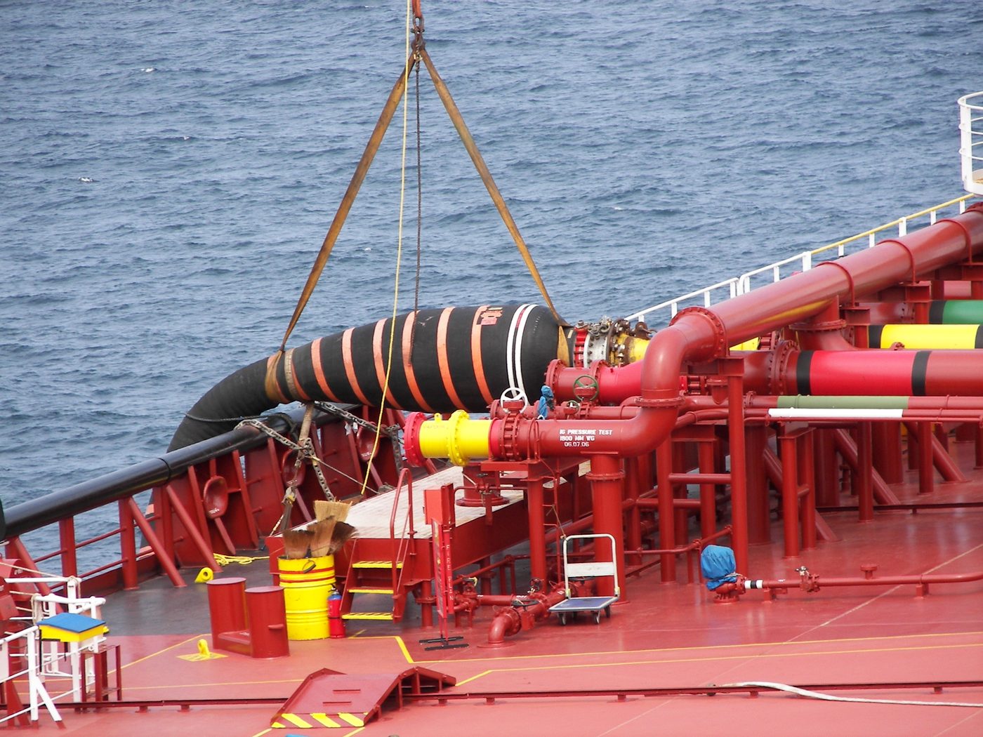 Cargo hose being rigged to the manifold with a crane sling
