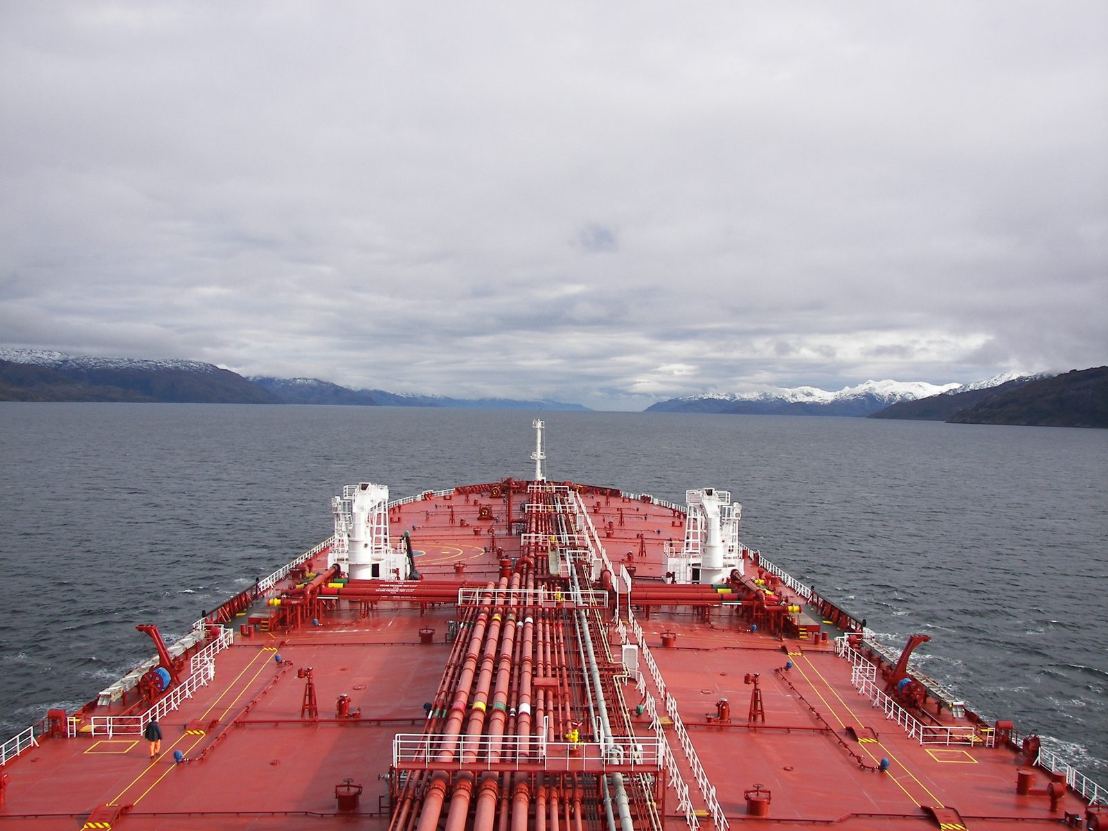 Tanker foredeck during passage through a fjord, mountains and pipeline visible