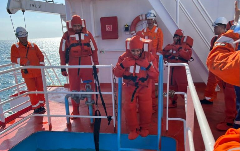Crew in immersion suits during an onboard emergency drill